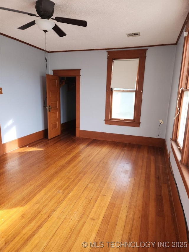 spare room featuring ceiling fan, light hardwood / wood-style flooring, ornamental molding, and a textured ceiling