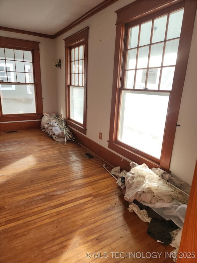 unfurnished room featuring plenty of natural light, ornamental molding, and light wood-type flooring