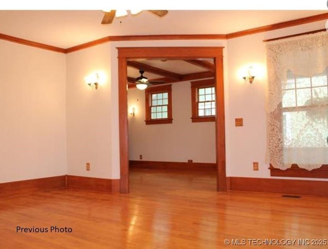 unfurnished room featuring beam ceiling, wood-type flooring, crown molding, and ceiling fan