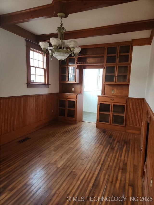 interior space featuring dark hardwood / wood-style flooring, a chandelier, beam ceiling, and a wealth of natural light