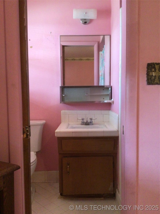 bathroom with tile patterned flooring, vanity, and toilet