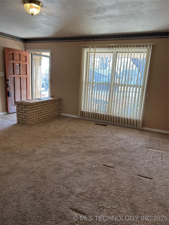 carpeted empty room with a textured ceiling