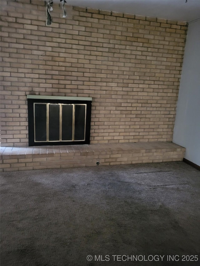 unfurnished living room featuring brick wall and carpet floors