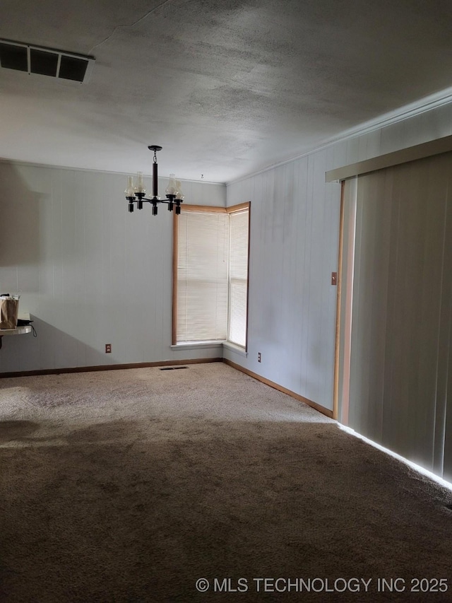 carpeted spare room featuring a chandelier and a textured ceiling