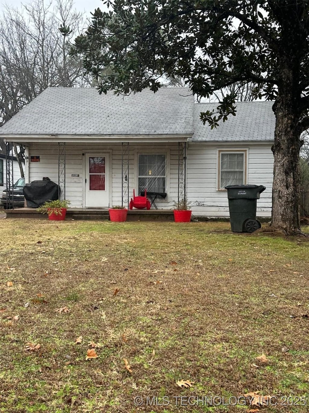 rear view of property featuring a porch and a yard