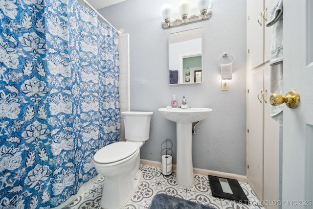 bathroom featuring tile patterned floors, toilet, curtained shower, and sink