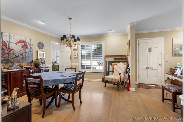 dining area featuring crown molding, a chandelier, and light hardwood / wood-style floors