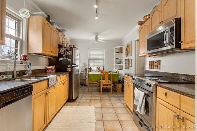 kitchen with ornamental molding, stainless steel appliances, sink, and dark stone counters