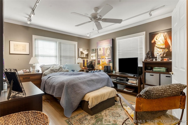 bedroom featuring ceiling fan, track lighting, ornamental molding, and light wood-type flooring