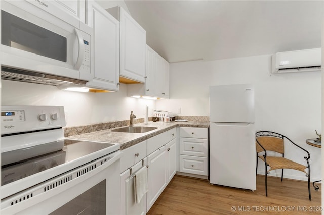 kitchen with sink, white cabinetry, an AC wall unit, white appliances, and light hardwood / wood-style floors