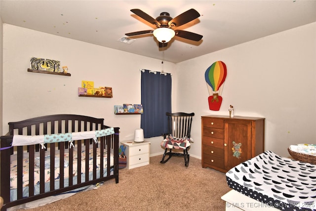 bedroom with ceiling fan, light carpet, and a crib