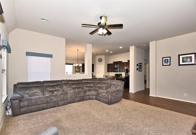 living room featuring ceiling fan with notable chandelier and dark colored carpet