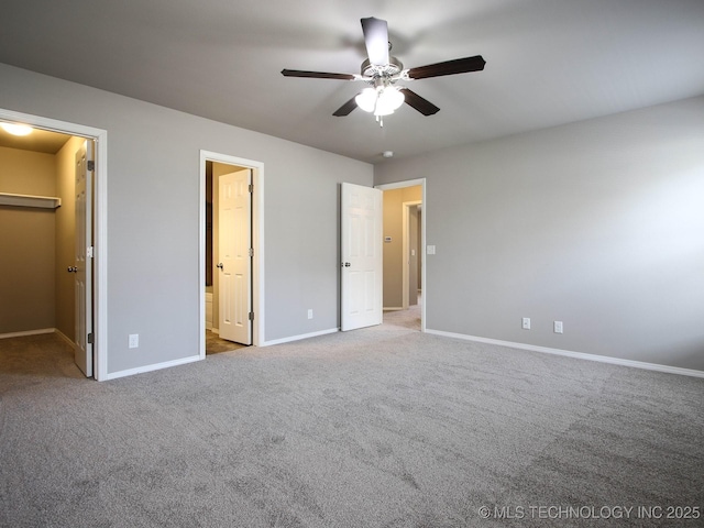 unfurnished bedroom featuring ceiling fan, a walk in closet, carpet floors, and ensuite bath