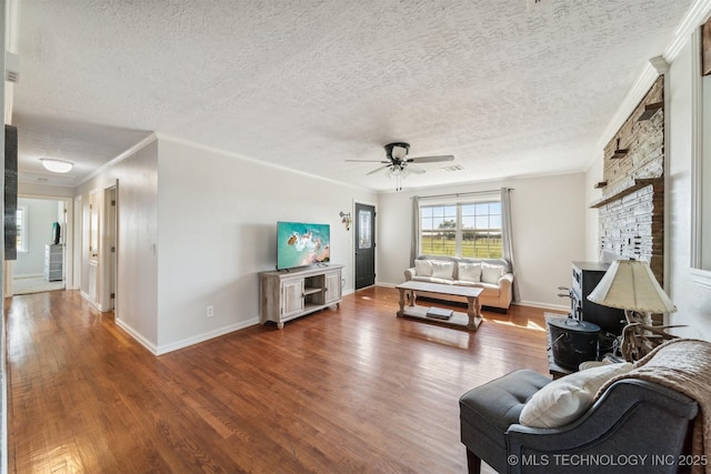 living area with wood finished floors, ceiling fan, ornamental molding, and a textured ceiling
