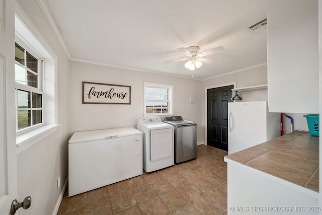 clothes washing area featuring crown molding, ceiling fan, a healthy amount of sunlight, and washer and clothes dryer