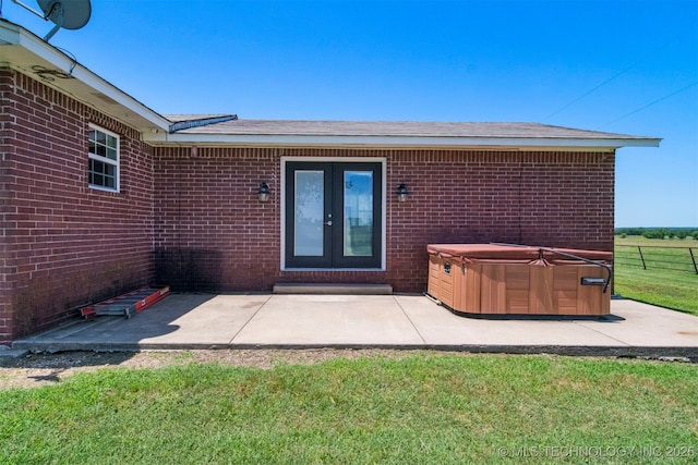 doorway to property featuring a yard, a patio, brick siding, and a hot tub