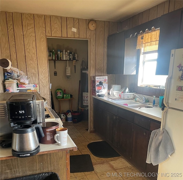 kitchen featuring sink, wooden walls, and white fridge