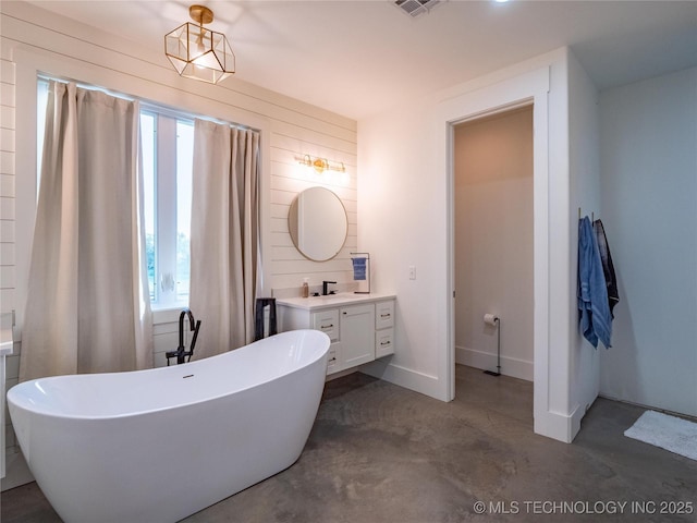 bathroom featuring a washtub, vanity, wooden walls, and concrete flooring