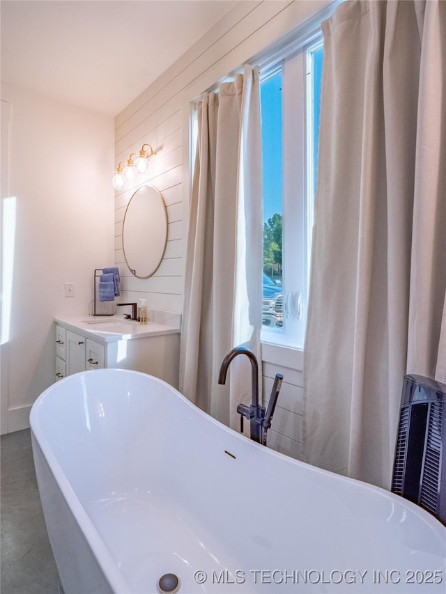 bathroom featuring vanity, a bathtub, and wood walls