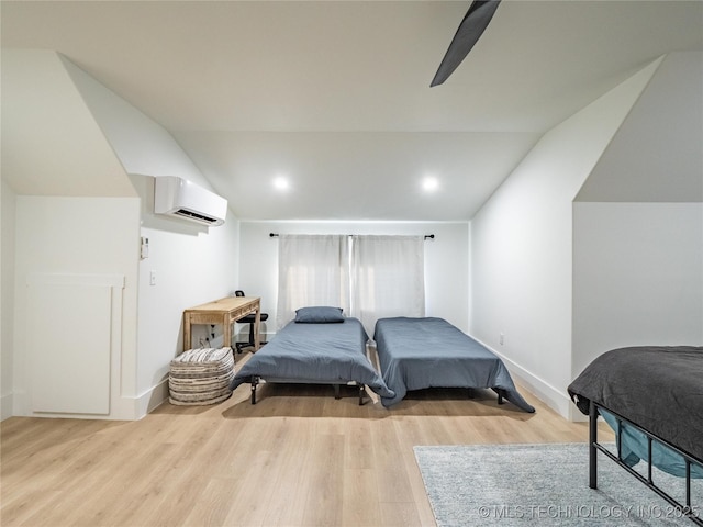 bedroom with a wall mounted AC, vaulted ceiling, and light hardwood / wood-style flooring