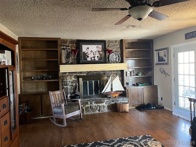 interior space featuring dark wood-type flooring, a textured ceiling, ornamental molding, ceiling fan, and a fireplace