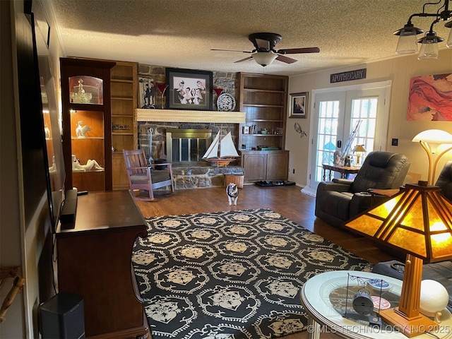 living room featuring dark hardwood / wood-style floors, a fireplace, ceiling fan, a textured ceiling, and french doors