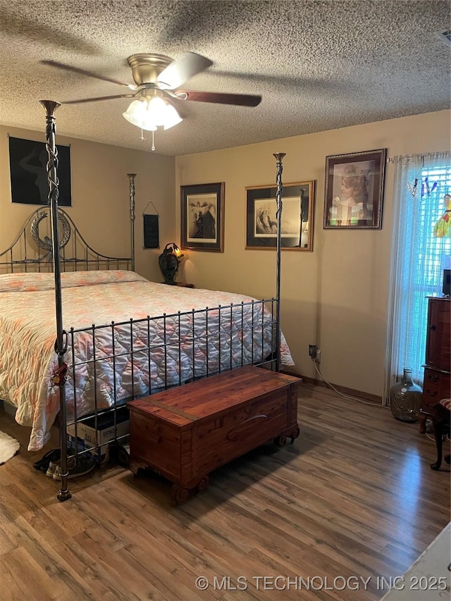 bedroom with ceiling fan, wood-type flooring, and a textured ceiling