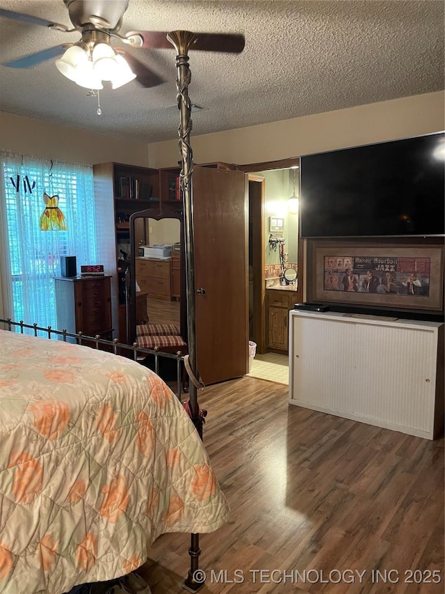 bedroom with ensuite bathroom, radiator, hardwood / wood-style floors, ceiling fan, and a textured ceiling