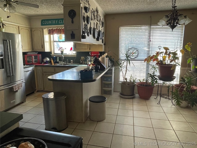 kitchen featuring light tile patterned floors, appliances with stainless steel finishes, a textured ceiling, kitchen peninsula, and light brown cabinets