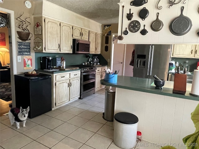 kitchen featuring light tile patterned flooring, stainless steel appliances, and a textured ceiling