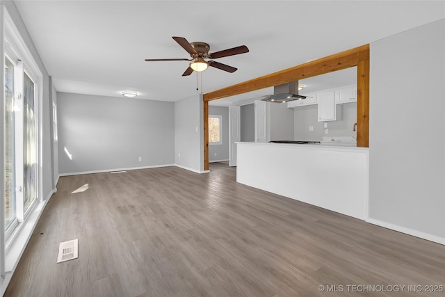 unfurnished living room featuring dark wood-type flooring and ceiling fan