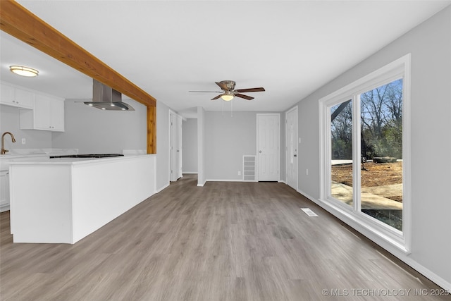 unfurnished living room with sink, light hardwood / wood-style floors, and ceiling fan