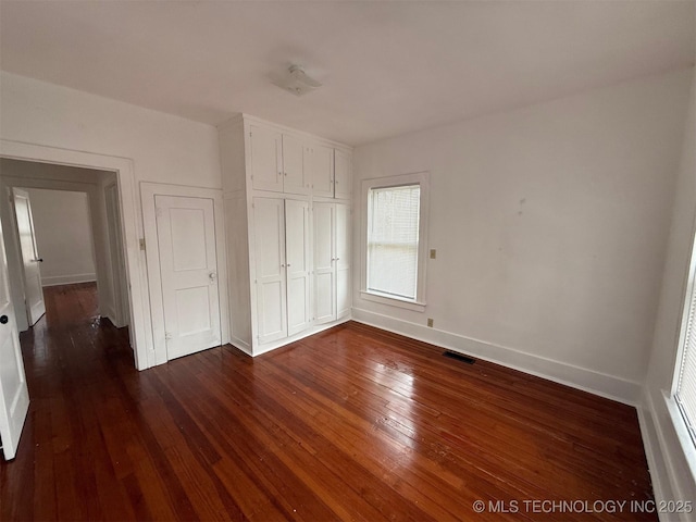 unfurnished bedroom with dark hardwood / wood-style flooring and a closet