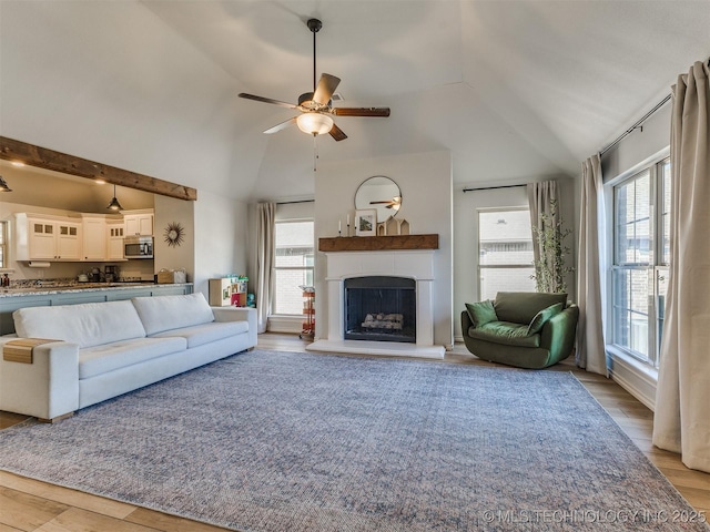 unfurnished living room with ceiling fan, vaulted ceiling, and light wood-type flooring