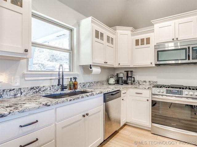 kitchen featuring white cabinetry, stainless steel appliances, sink, and light stone counters