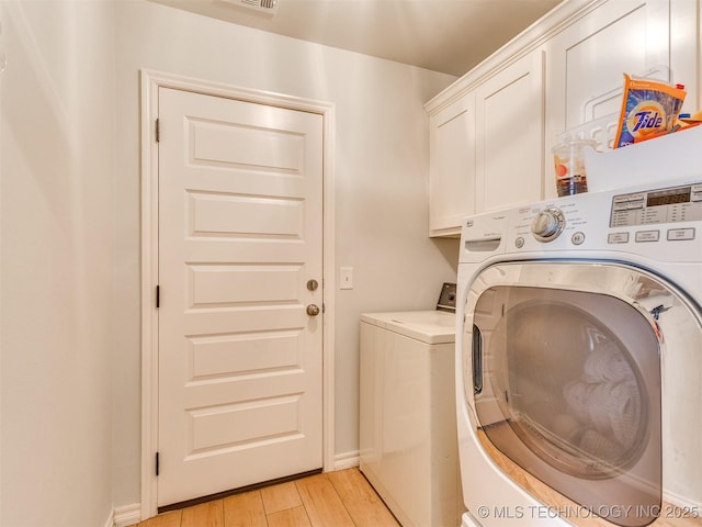 laundry room featuring cabinets, washing machine and clothes dryer, and light wood-type flooring