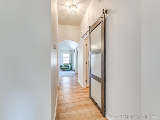 corridor with light hardwood / wood-style flooring and a barn door