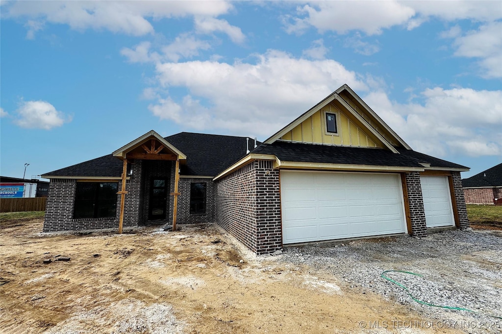 view of front facade featuring driveway, brick siding, and board and batten siding