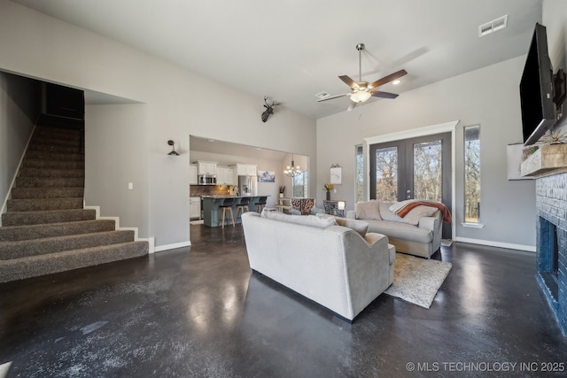 living room featuring high vaulted ceiling, a fireplace, and ceiling fan with notable chandelier