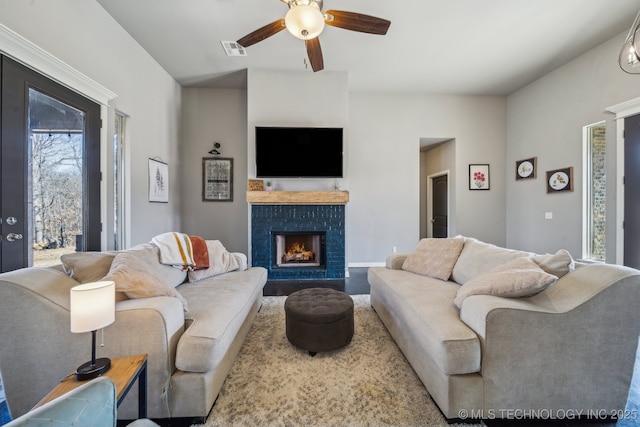 living room with hardwood / wood-style flooring, a brick fireplace, and ceiling fan