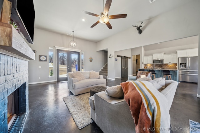 living room with a towering ceiling, a fireplace, french doors, and ceiling fan