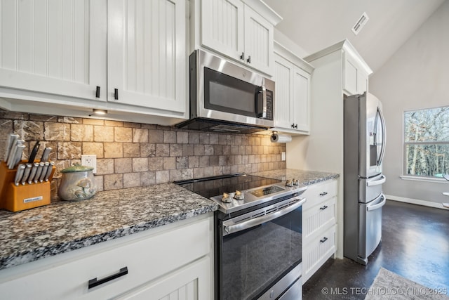 kitchen featuring stainless steel appliances, decorative backsplash, white cabinets, and dark stone counters