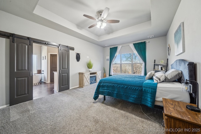 carpeted bedroom featuring ceiling fan, a barn door, and a raised ceiling