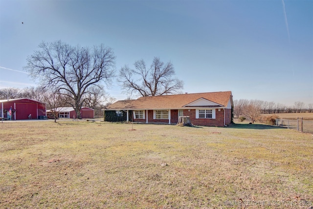 single story home featuring a front lawn and a storage shed