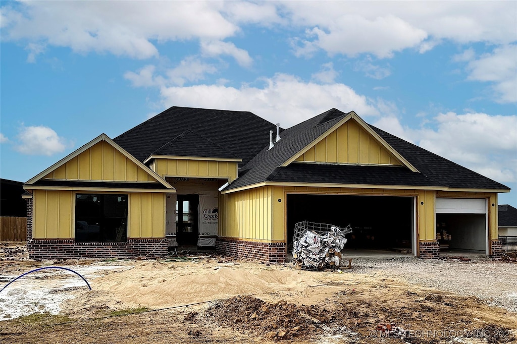 view of front facade featuring a garage, driveway, brick siding, and roof with shingles