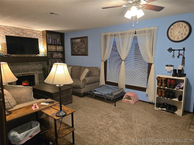 living room with ceiling fan, carpet flooring, a fireplace, and a textured ceiling