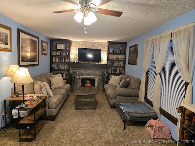 living room featuring ceiling fan, a stone fireplace, carpet floors, and a textured ceiling