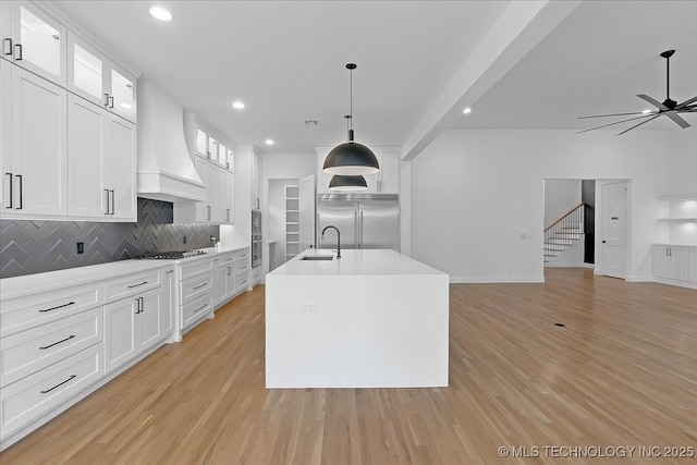 kitchen featuring stainless steel appliances, premium range hood, pendant lighting, and white cabinetry