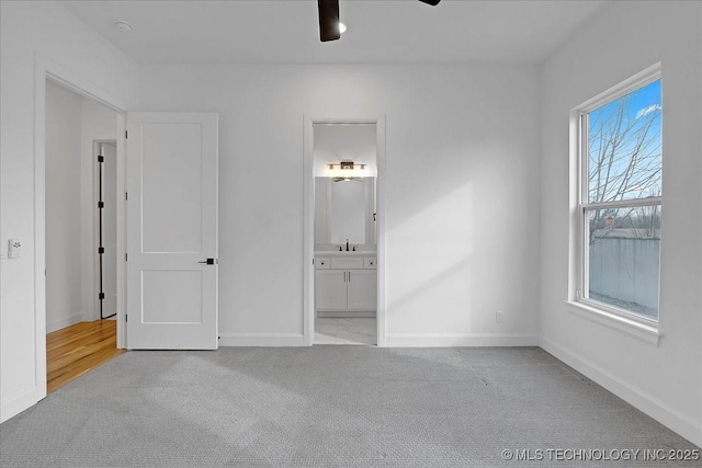 unfurnished bedroom with ceiling fan, connected bathroom, and light colored carpet