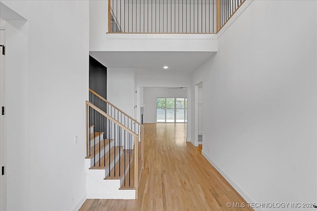 corridor with a towering ceiling and light hardwood / wood-style flooring